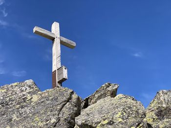 Low angle view of cross on rock against sky