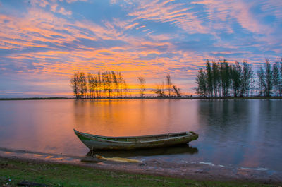 Beautiful view of lake against sky at sunset with old boat object