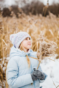 Woman wearing hat standing on field during winter