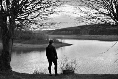 Rear view of man standing at lakeshore