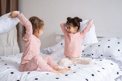 Cute sisters pillow fighting on bed