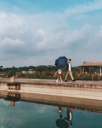 People standing by swimming pool against sky