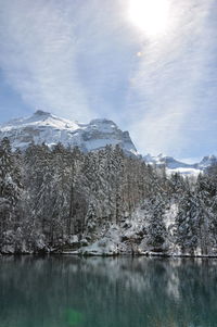 Scenic view of lake by snowcapped mountains against sky