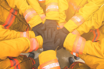 High angle view of firefighters with gloves stacking hands in unity
