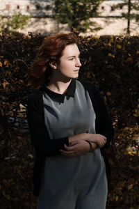 Young woman looking away while standing on land