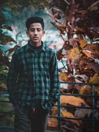 Portrait of young man standing against tree