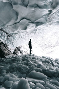 Side view of young woman standing on rock in cave