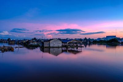 Reflection of houses and buildings against sky during sunset