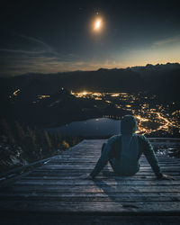 Rear view of woman against sky at night