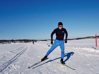 Full length of man on snowy field against clear blue sky