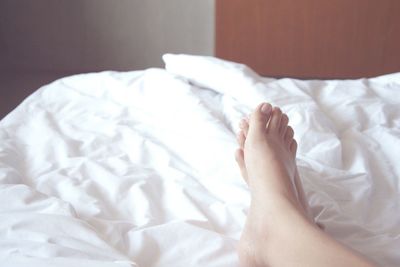 Low section of woman lying on bed