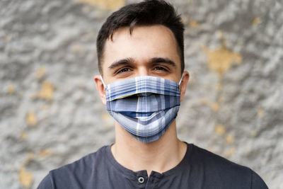 Portrait of young man covering face against wall