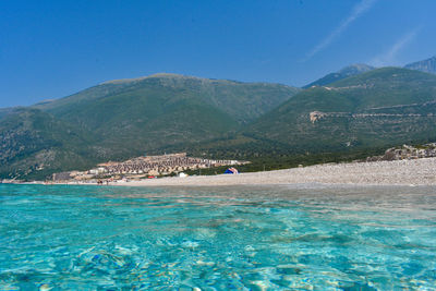 Scenic view of sea and mountains against blue sky