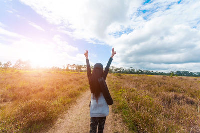 Rear view of woman gesturing peace sign while standing on field