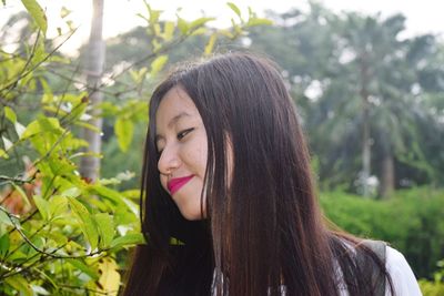 Smiling young woman looking at plant