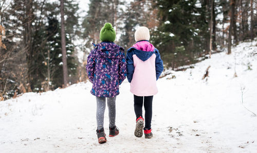 Rear view of women walking on snow covered land