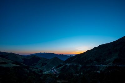 Scenic view of silhouette mountains against clear sky at sunset