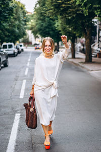 Portrait of smiling young woman walking on road in city