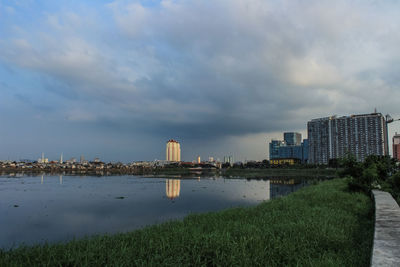Scenic view of river by buildings against sky
