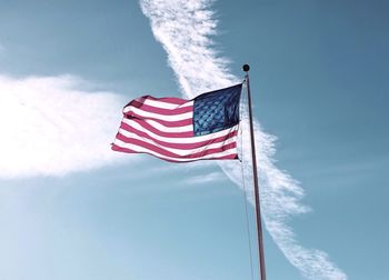 Low angle view of american flag waving against sky