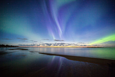 Aurora borealis over river against sky at night