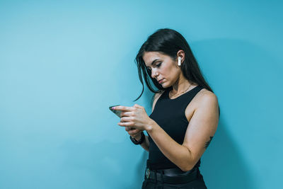 Young woman standing against blue background