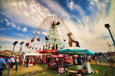 People in amusement park against sky