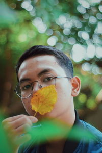 Portrait of man holding leaf over mouth