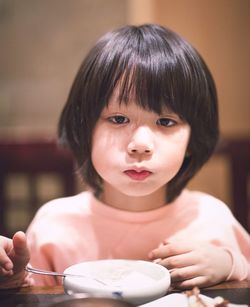 Close-up portrait of cute boy standing by dining table