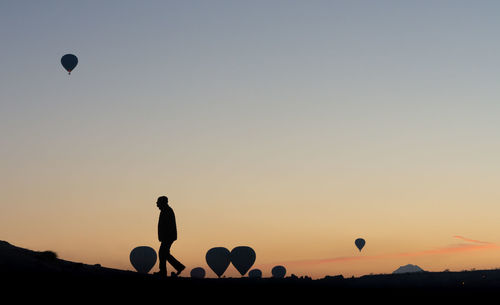 Silhouette of hot air balloons against sky during sunset