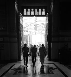 Rear view of men walking in corridor of building