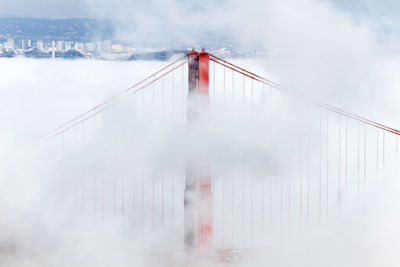 Suspension bridge in city against sky