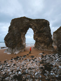 Rock formations on beach against sky