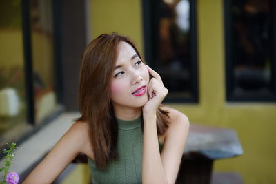 Thoughtful young woman looking away while sitting in cafe