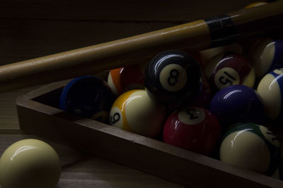 Close-up of balls with rack and pool cue on table