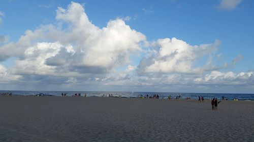 Panoramic view of people on beach against blue sky