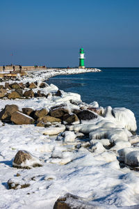 Lighthouse by sea against clear sky