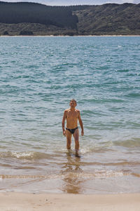 Shirtless man wading in sea