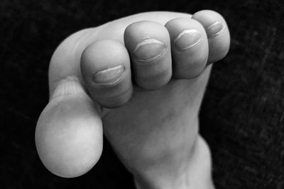 Low section of child with hand on black background