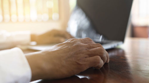 Cropped hands of man using laptop on table