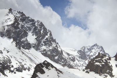Rocky pointed mountain peaks in the snow, close, the sky in the clouds, winter, day