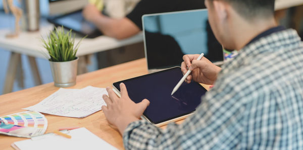 Midsection of man using mobile phone on table