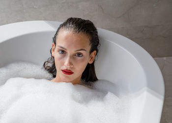 Portrait of woman wearing red lipstick relaxing in bath