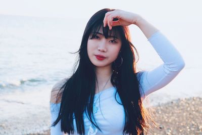 Portrait of beautiful young woman standing on beach