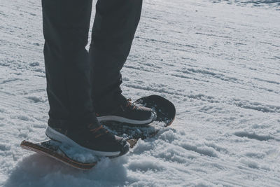 Low section of man skiing on snow covered field