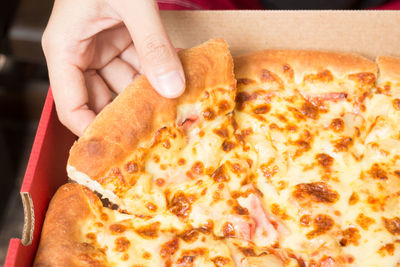 Close-up of hand holding pizza