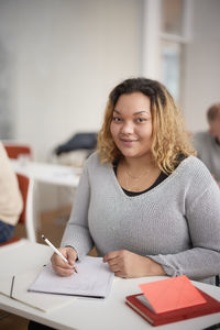 Portrait of woman making notes in class