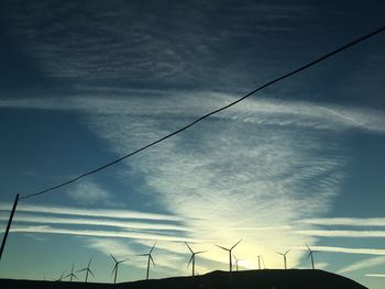 Low angle view of electricity pylon against sky during sunset