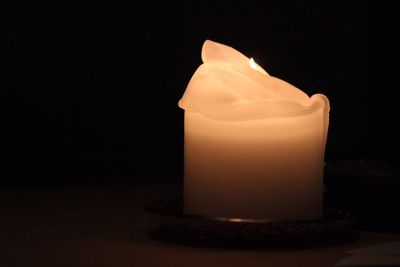 Close-up of burning candle against black background