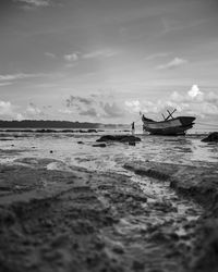 Fishing boat on beach against sky